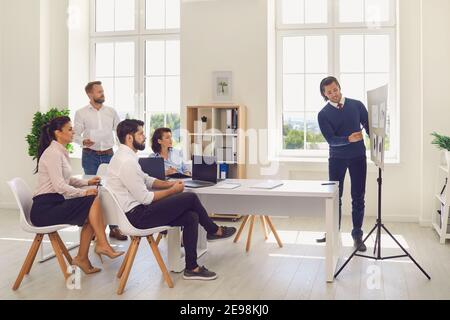 Junger männlicher Vertriebsleiter, der für Mitarbeiter in einer Präsentation vorführt Ein Unternehmensmeeting Stockfoto