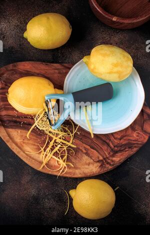Zitronenschale und Reibe auf einem Holzbrett auf schwarzem Hintergrund. Selektiver Fokus. Stockfoto