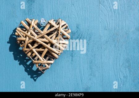 Feier- und Special Event-Konzept: Draufsicht auf einen einzelnen Holz-Stroh-Herzkranz. Hintergrund in Holzblau mit großem Kopierraum. Liebe Stockfoto