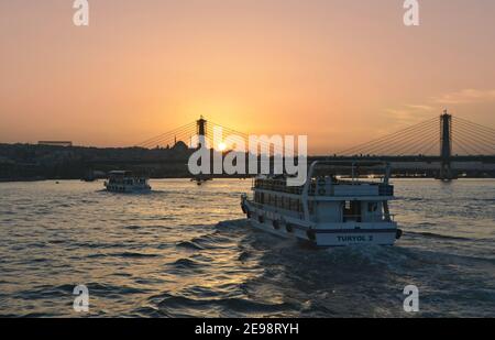 Sonnenuntergang Meereslandschaft mit traditionellen Tour Boote Kreuzfahrt auf Bosporus, Panoramablick auf Atatürk Brücke und Süleymaniye Moschee in Istanbul, Türkei. Stockfoto