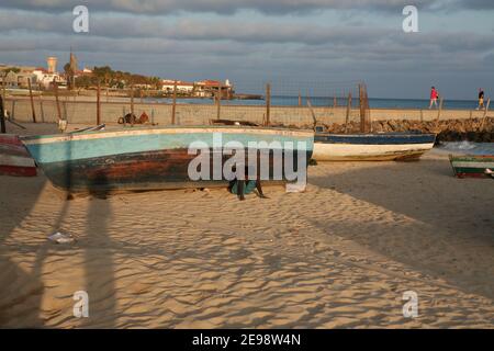 Boot auf dem Sandstrand. Ein Fischer, der mit dem Boot arbeitet oder sonst nur seine Zeit in Santa Maria, Sal Island, Kap Verde, Afrika verbringt. Stockfoto