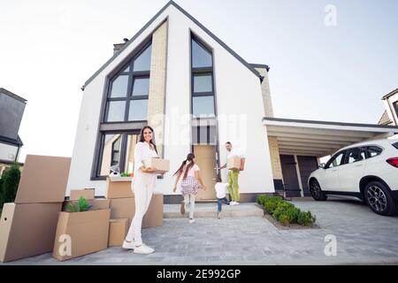 Blick vom Balg der großen Familie mit kleinen spielerischen Eintritt Haus bewegt Papa hält Türen halten Boxen Mama lächelnd draußen Stockfoto