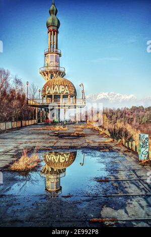 Ende einer Idee. Unvollendeter Turm und Kuppel spiegeln sich in einem Wasserbecken in der verlassenen Stadt Consonno. Stockfoto