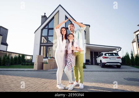 Foto-Porträt von glücklichen Eltern mit kleinen Tochter zeigt wie Daumen-up-Zeichen vor dem neuen Haus Sommer gemütliche Versicherung Sicher Stockfoto