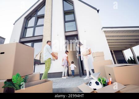 Blick von unten auf Eltern mit Kisten beim Betreten des neuen Hauses Mit verspielten kleinen Bruder Schwester Kinder Stockfoto