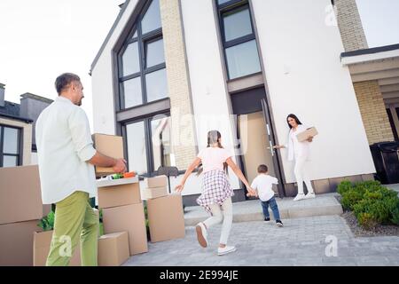 Blick von unten auf große fröhliche Familie Umzug Neues Haus auf Hypothek mit Paketen Boxen Kinder spielen draußen Stockfoto