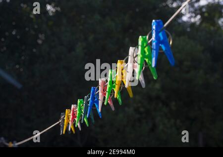 Reihe von bunten Wäscheklammern auf einer Wäscheleine auf einem schwarzen Hintergrund Stockfoto