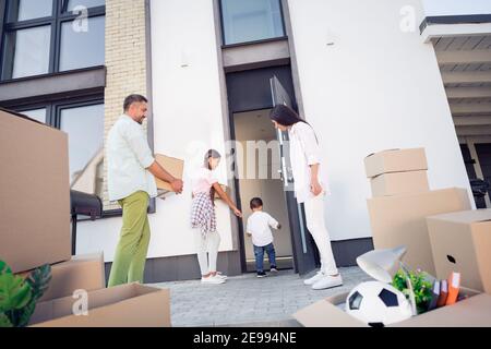 Blick von unten auf voll glückliche Familie Eltern mit wenig Kinder, die neue Heimat mit Packungen Boxen Stockfoto