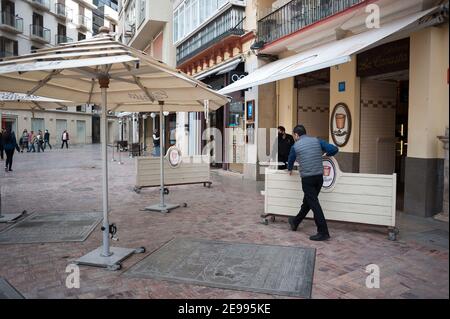 Malaga, Spanien. Februar 2021, 3rd. Die Arbeiter sahen, wie sie Bretter hoben, um ein Café an einem leeren Platz auf der Plaza de la ConstituciÃ³n zu schließen, inmitten der teilweisen Sperrung, die durch eine Coronavirus-Pandemie verursacht wurde. Kredit: Jesus Merida/SOPA Images/ZUMA Wire/Alamy Live Nachrichten Stockfoto