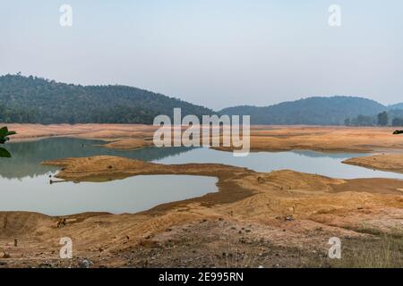 Ein ländlicher indischer kleiner See haben sehr weniger Wasser mit viel Grün Bergwald Hintergrund. Stockfoto