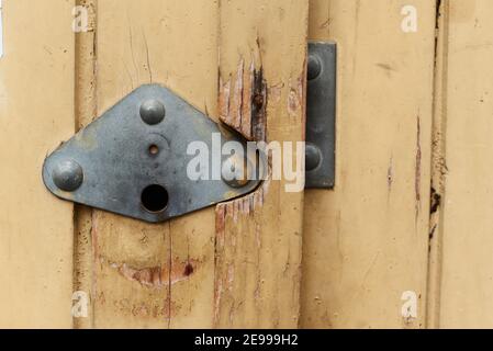 Nahaufnahme der gelben alten Holztür mit Metallgriff Garage Antike balkan im Alter mit verrosteten Metallstangen Stockfoto