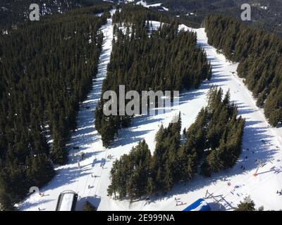 Luftaufnahme vom Turm Sneschanka, in der Nähe von Pamporovo, Bulgarien zu den Skipisten mit Skifahrer auf ihnen. Stockfoto