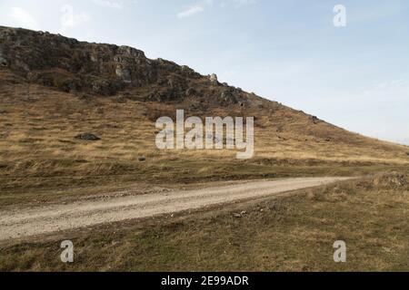 Das Landschaftsfoto, das im Spätherbst aufgenommen wurde. Der Steinhügel und die Landstraße. Stockfoto