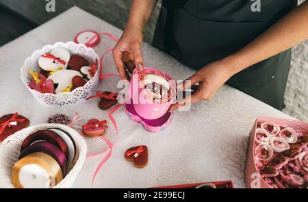 Mädchen verpackt in einer Geschenkbox Kuchen in Form eines Herzens. Vorbereitung auf die Feier. Stockfoto