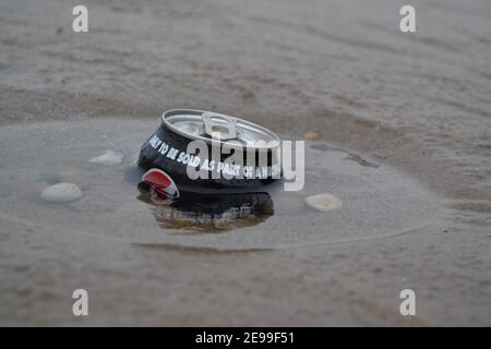 Alkoholfreie Getränke können an Einem Strand zurückgelassen werden - in den Sand geschoben - Müll - Wurf im Sand - Kieselsteine / Steine / Sand - Abfallverschmutzung - Yorkshire - Großbritannien Stockfoto