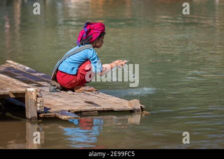 Inle Lake, Myanmar - Dezember 2019: Mädchen sitzt am Flussufer Stockfoto