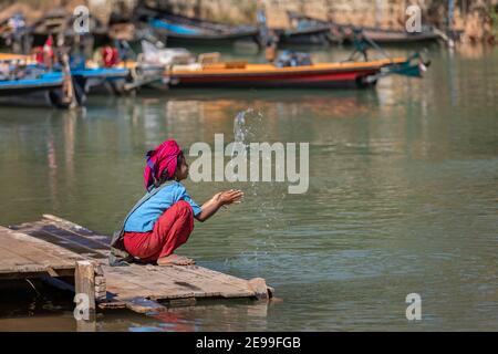 Inle Lake, Myanmar - Dezember 2019: Mädchen sitzt am Flussufer Stockfoto