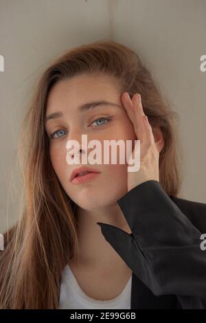 Hochdetaillierte Aufnahme von zarten schönen niedlichen jungen Weibchen mit brünetten langen Haaren, blauen Augen und einigen Sommersprossen auf ihrem ganzen Gesicht posiert im Freien. Stockfoto