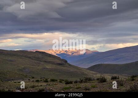 Moody Sonnenuntergang über den andenbergen des Torres del Paine Nationalparks mit goldenem Sonnenlicht und dramatischen Wolken am Himmel, Chile Südamerika Stockfoto