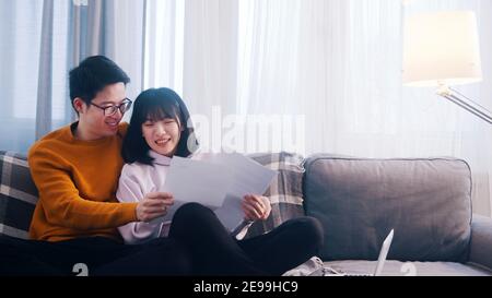 Glückliches junges Paar, das sich auf der Couch entspannt und Papiere anschaut. Hochwertige Fotos Stockfoto