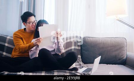 Junges Paar über Finanzen diskutieren. Frau hält Rechnungen, während Mann mit Laptop. Hochwertige Fotos Stockfoto