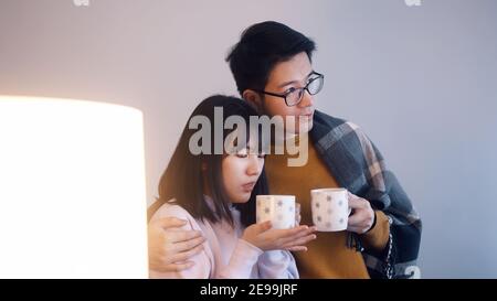 Junge asiatische paar trinken heißen Tee und beobachten einen Film. Liebe und Zuneigung Konzept . Hochwertige Fotos Stockfoto