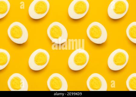 Frische Farm Huhn gekocht halb geschnitten Eier Muster auf gelbem Hintergrund. Gesundes Essen oder Happy Easter kreatives Minimalkonzept. Flach liegend, Draufsicht Stockfoto