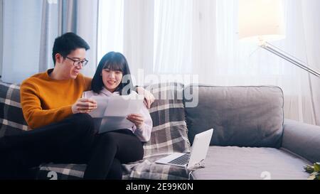 Glückliches junges Paar, das sich auf der Couch entspannt und Papiere anschaut. Hochwertige Fotos Stockfoto