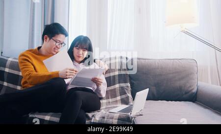 Glückliches junges Paar, das sich auf der Couch entspannt und Papiere anschaut. Hochwertige Fotos Stockfoto
