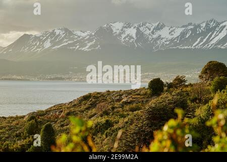 Ushuia ist das Ende der Welt in feuerland. Stadt liegt vor den schneebedeckten Bergen der Anden mit üppiger grüner Vegetation in Gold Stockfoto