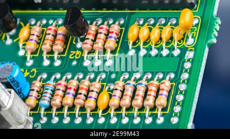 Nahaufnahme der Leiterplatte mit elektronischen Komponenten. Elektrotechnik. Farbenfrohe Widerstände mit Standard-Farbcode, Kondensatoren und Transistoren. Stockfoto