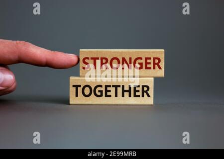 Stärker zusammen Symbol. Konzeptworte "stärker zusammen" auf Holzblöcken auf einem schönen grauen Hintergrund. Geschäftsmann Hand. Geschäft, Motivation Stockfoto