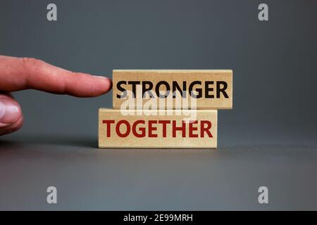 Stärker zusammen Symbol. Konzeptworte "stärker zusammen" auf Holzblöcken auf einem schönen grauen Hintergrund. Geschäftsmann Hand. Geschäft, Motivation Stockfoto