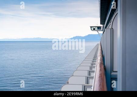 Ein Blick auf das Meer und schneebedeckte Berge entlang der Küste von Alaska, gesehen vom Balkon eines Kreuzfahrtschiffes Stockfoto