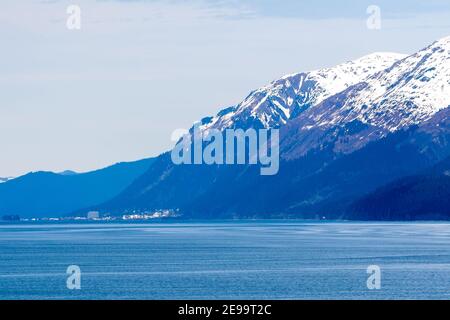 Schneebedeckte Berge und kleine Stadt entlang der Küste des südlichen Alaska Stockfoto