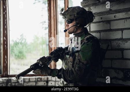 Waffeninspektion während des Wartens an einer Stelle. Militärmann überprüft sein Sturmgewehr, um sich auf den Betrieb vorzubereiten. Stockfoto