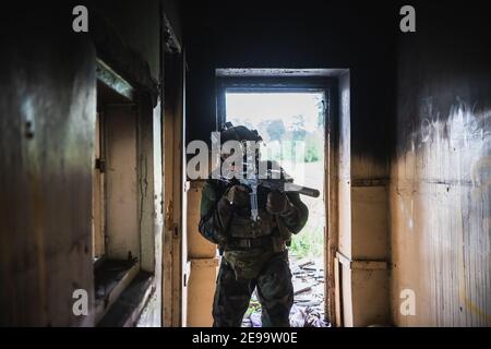 Soldat in voller US-MARSOC-Ausrüstung in verlassene Gebäude betreten, mit verschiedenen Winkeln mit MK18 Sturmgewehr zielen Stockfoto