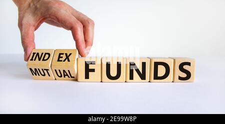 Index vs. Investmentfonds-Symbol. Geschäftsmann dreht einen Würfel und ändert die Wörter "Mutual Funds" in "Index Funds. Schöner weißer Hintergrund, Kopierbereich. Busin Stockfoto