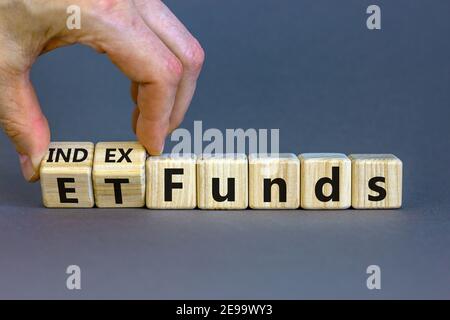 Indexfonds vs. ETF-Symbol. Geschäftsmann dreht einen Würfel und ändert die Wörter „ETF, Exchange-Traded Fund“ in „Indexfonds“. Schöner grauer Hintergrund, kopieren Spa Stockfoto