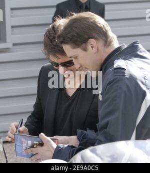 US-Schauspieler Tom Cruise signiert am 26. April 2006 ein Autogramm auf einem DVD-Cover von "Top Gun" an einen französischen Polizisten am Hubschrauberlandeplatz von Issy les Moulinaux in der Nähe von Paris. Kreuzfahrt beschließt, die französische Premiere 'Mission Impossible III' mit dem Hubschrauber zu verbinden. Foto von Bruno Klein/ABACAPRESS.COM Stockfoto