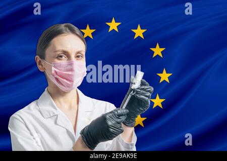 Ärztin bereitet die Impfung vor dem Hintergrund der EU-Flagge vor. Impfkonzept Europäische Union. Stockfoto