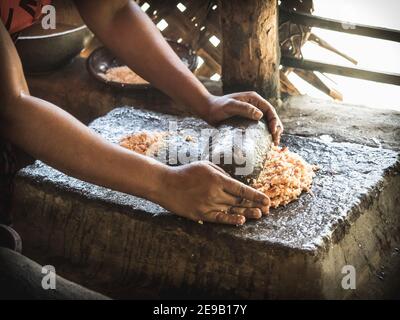 HIRIWADUNNA, SRI LANKA - 10. März 2019: Junge südasiatische Frau kocht Reis und Curry in der traditionellen ländlichen Outdoor-Küche. Stockfoto