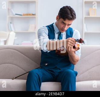 Der junge Musiker Mann spielen Geige Üben zu Hause Stockfoto