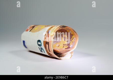 50 Euro-Scheine rollten in eine Rolle auf grauem Hintergrund mit Kopierraum, Finanzierungskonzept, ausgewähltem Fokus, enger Schärfentiefe Stockfoto