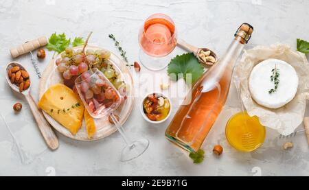 Rosa Wein Rose gereifte Käse Camembert Käse Nüsse Honig rote Trauben Gläser Wein. Köstliches Essen Wein Snacks sortiert auf Brettern serviert. Flach liegend lang Stockfoto