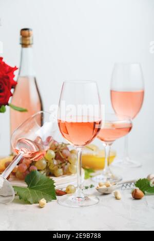 Roséwein in verschiedenen Gläsern auf hellgrauem Betongrund. Minimale Weinkomposition auf weißem Tisch. Stockfoto