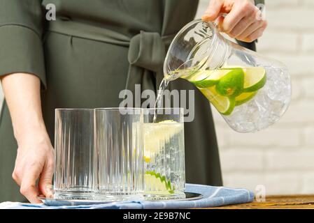 Frau Gießen Obst infundiert Wasser aus Glas Jag zu Glas, Getränke, Diät, Entgiftung Konzept Stockfoto