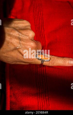 Weibliche Hand mit einem orangefarbenen Ring auf einem orangefarbenen Deckel Stockfoto