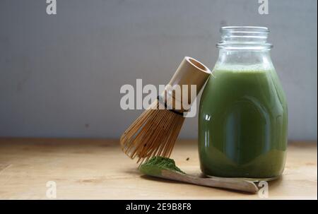 Frisches, erfrischendes und biologisches Matcha-Pulver, das in frische Kokosmilch geschmundert wird. Schneebesen und geschöpft mit klassischen Bambusutensilien. Stockfoto