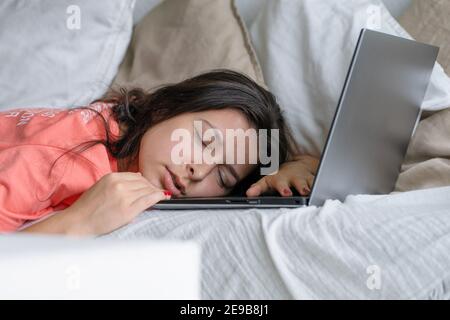 Das Mädchen schlief während der Arbeit auf einem Laptop ein. Schlaf während der Arbeitszeit. Probleme mit Freiberuflern. Stockfoto